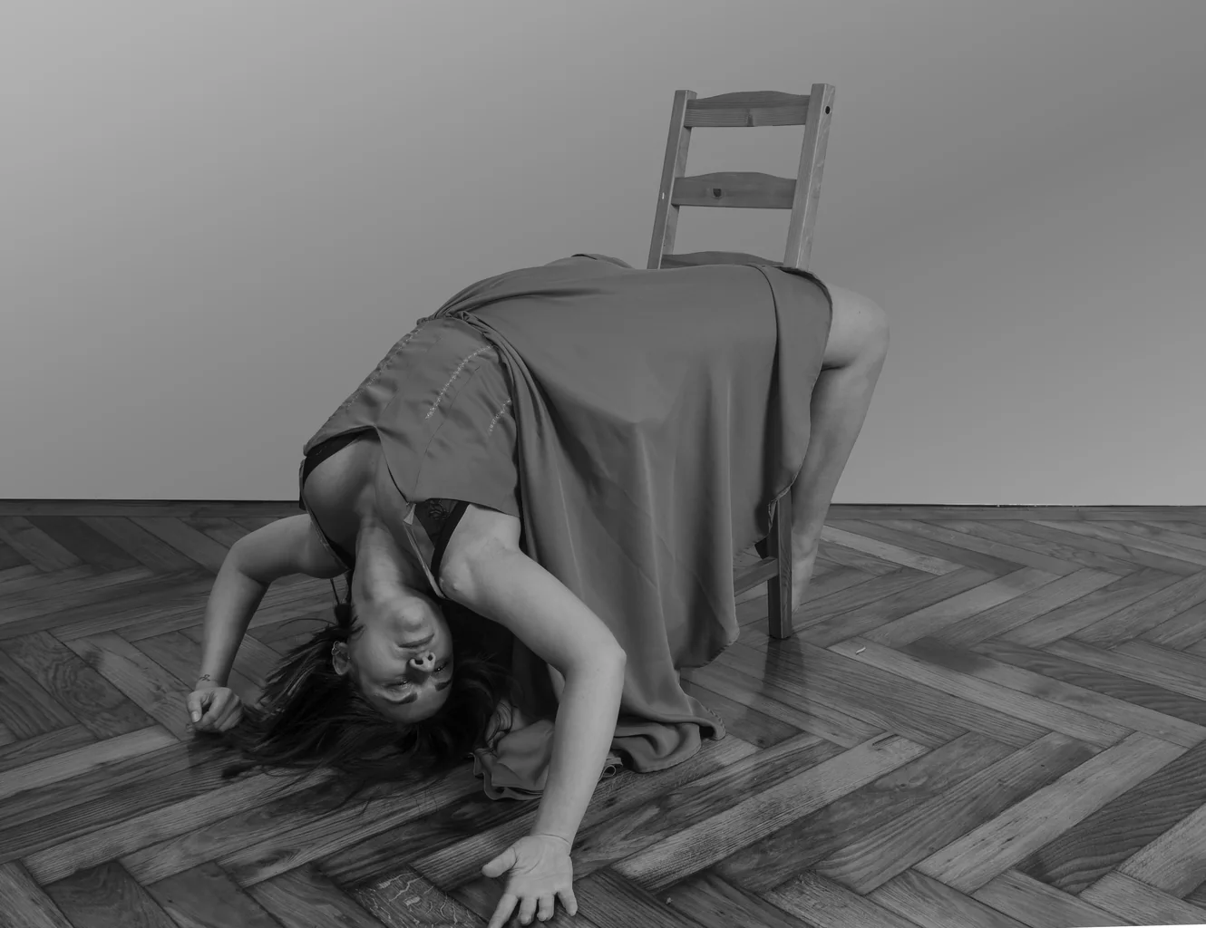 Arched backwards over a chair in a grey dress