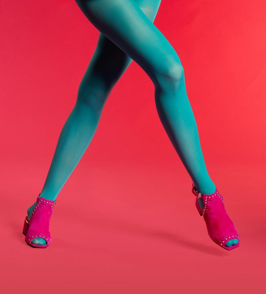Teal tights and pink studded heels mid-step on red