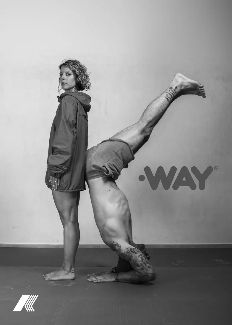 A standing model beside a performer in a handstand, beneath the WAY logotype