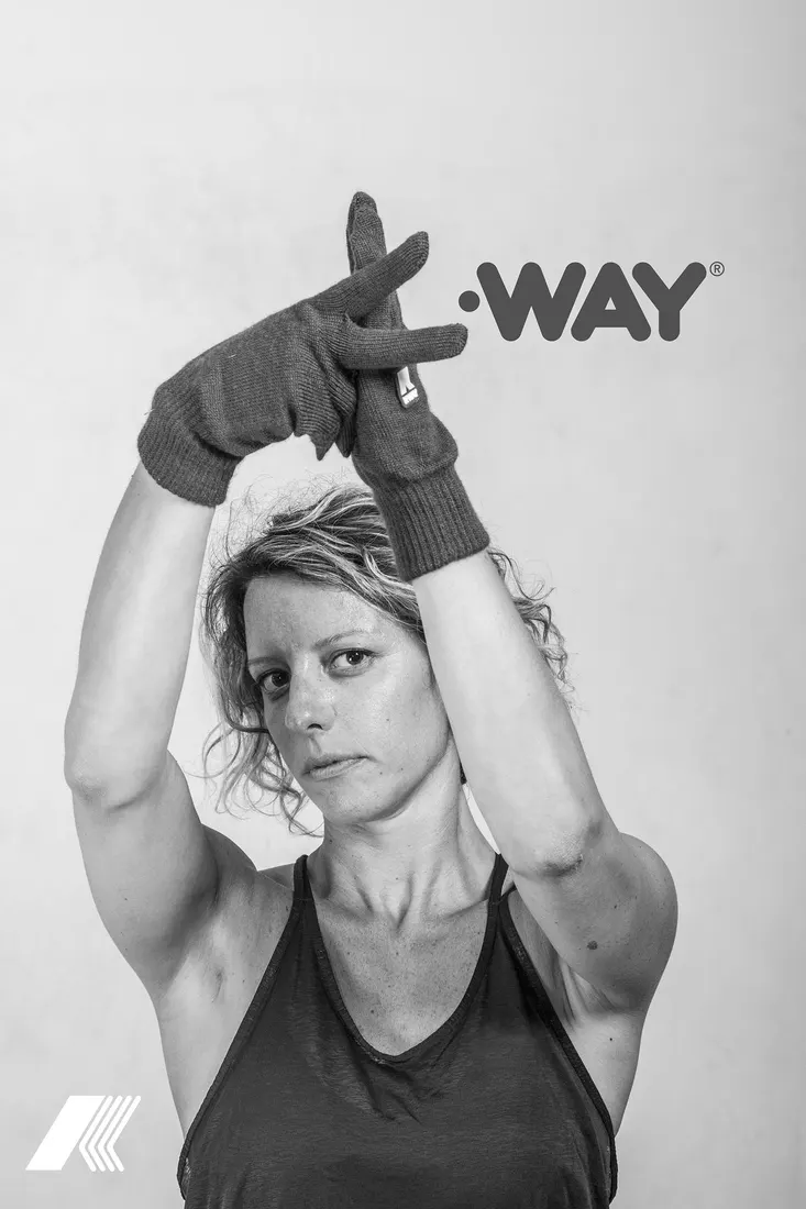 Model raising both arms in knitted K-WAY gloves to form a K