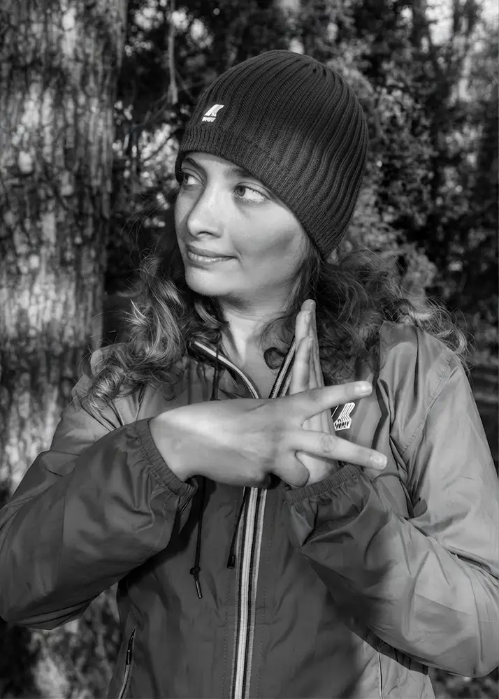 Model in a K-WAY beanie forming a K with her hands in the woods