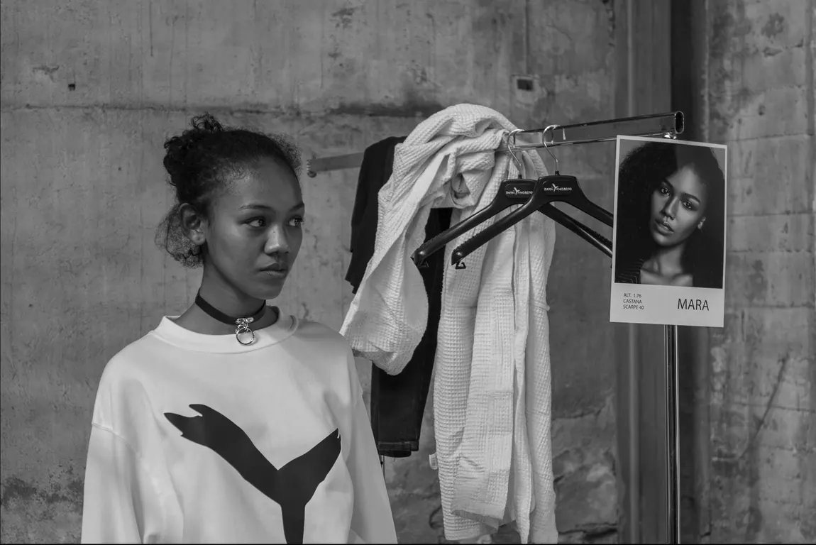 Model in a white sweatshirt waiting beside the rails
