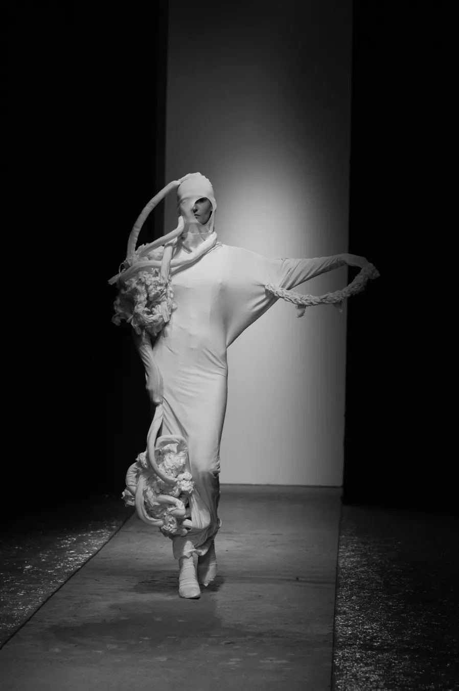 White sculptural gown with a hood on the runway